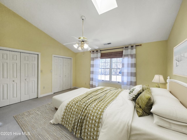 bedroom with two closets, lofted ceiling with skylight, baseboards, visible vents, and a ceiling fan