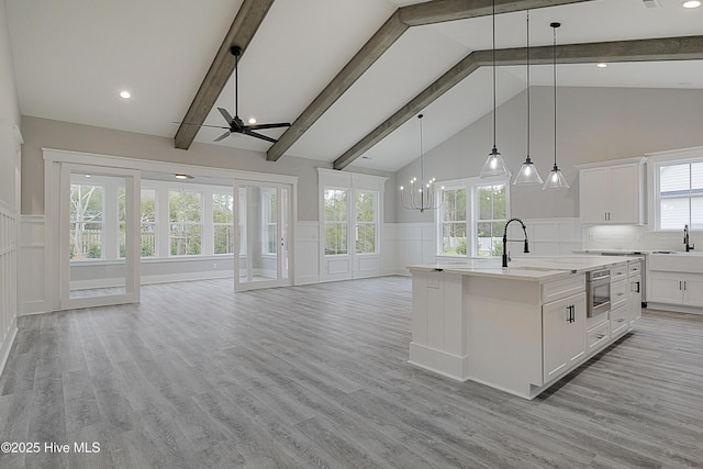 kitchen with beamed ceiling, ceiling fan with notable chandelier, open floor plan, and built in microwave