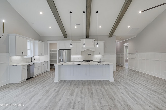 kitchen featuring beamed ceiling, appliances with stainless steel finishes, light wood-style flooring, and light countertops