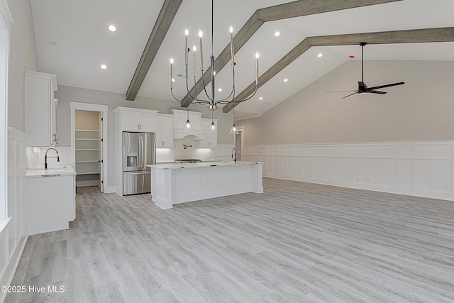 kitchen with open floor plan, a sink, light countertops, and stainless steel fridge with ice dispenser