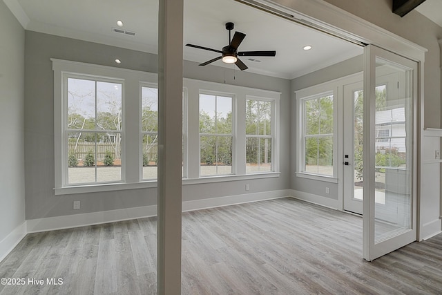 unfurnished sunroom featuring a wealth of natural light, visible vents, and ceiling fan