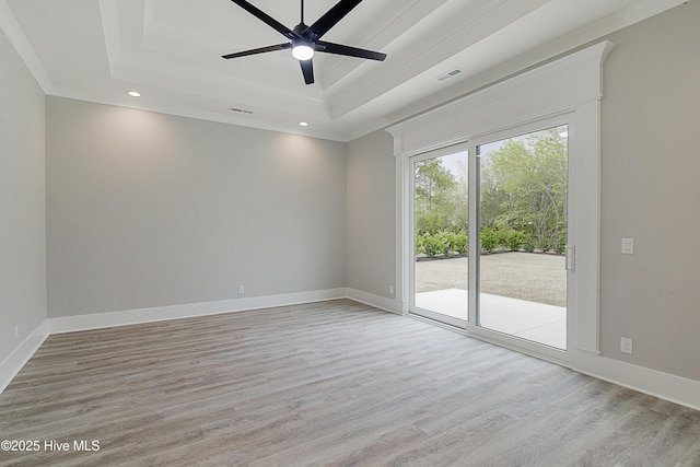 spare room with visible vents, baseboards, ceiling fan, light wood-style floors, and a raised ceiling