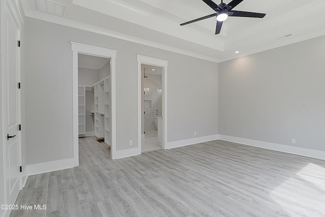 unfurnished bedroom featuring a walk in closet, baseboards, and wood finished floors