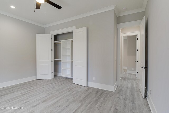 unfurnished bedroom with a closet, crown molding, light wood-type flooring, and baseboards