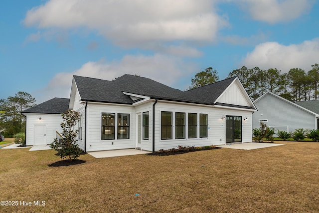 back of house with board and batten siding, a patio area, a lawn, and roof with shingles