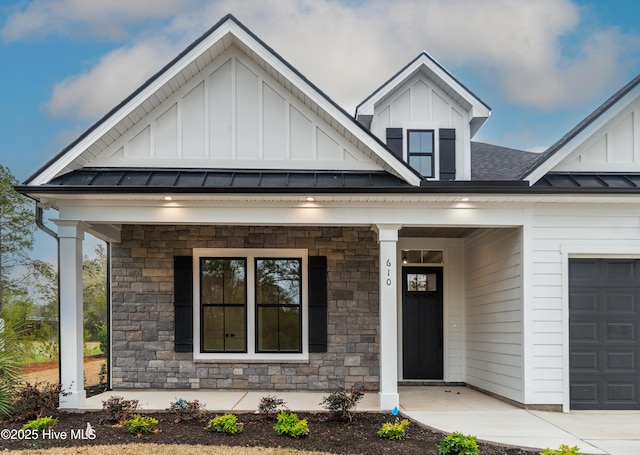 view of front of home with a standing seam roof, a porch, board and batten siding, and stone siding