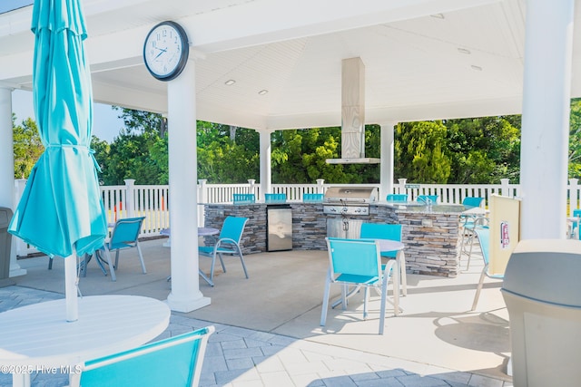 view of patio with outdoor dining space, a grill, outdoor wet bar, and fence