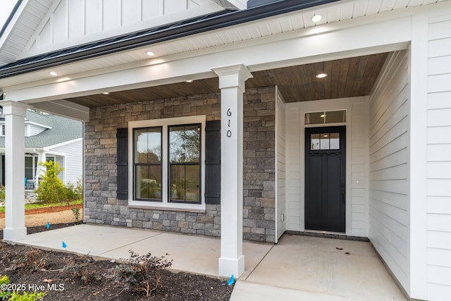 entrance to property featuring a porch, stone siding, and board and batten siding