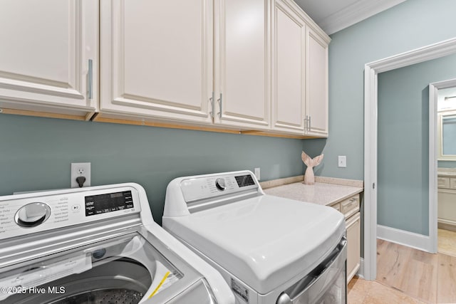 washroom featuring baseboards, washer and clothes dryer, and cabinet space