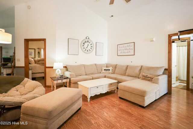 living area featuring light wood finished floors, high vaulted ceiling, and a ceiling fan