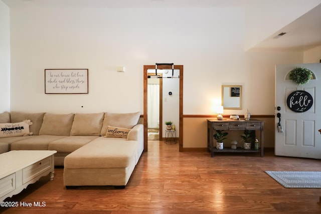 living room with wood finished floors, visible vents, and baseboards