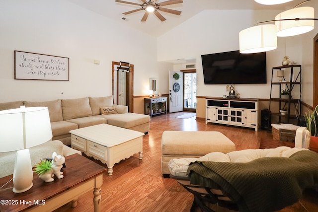 living room with wood finished floors, a ceiling fan, and high vaulted ceiling