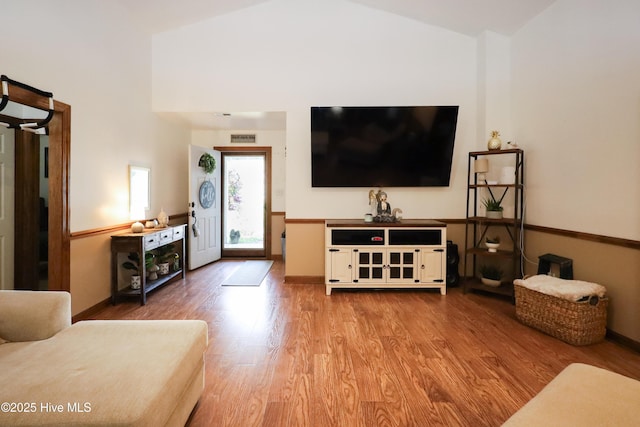 living room featuring visible vents, baseboards, wood finished floors, and high vaulted ceiling