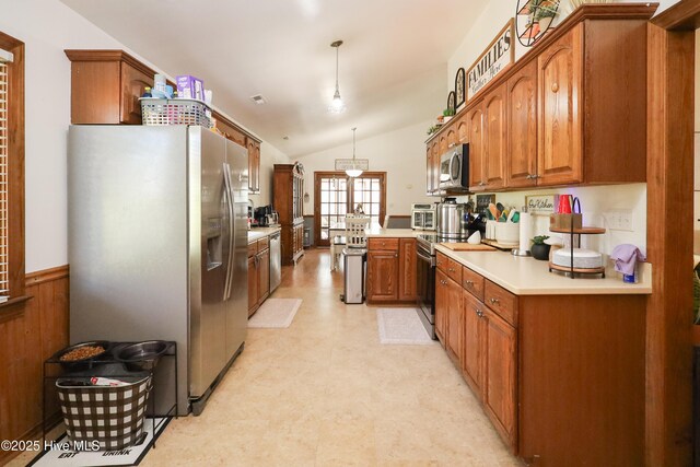 kitchen with brown cabinets, light floors, light countertops, lofted ceiling, and appliances with stainless steel finishes