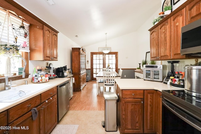 kitchen with a peninsula, light countertops, vaulted ceiling, and stainless steel appliances