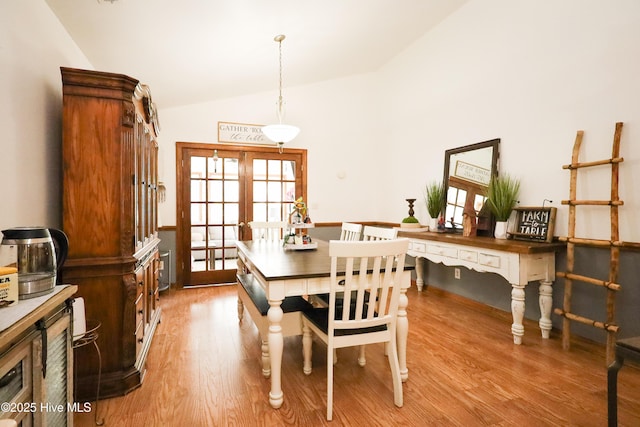 dining room featuring lofted ceiling, french doors, and light wood finished floors