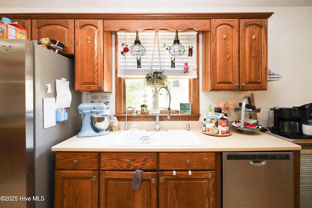 kitchen with brown cabinets, appliances with stainless steel finishes, a sink, and light countertops