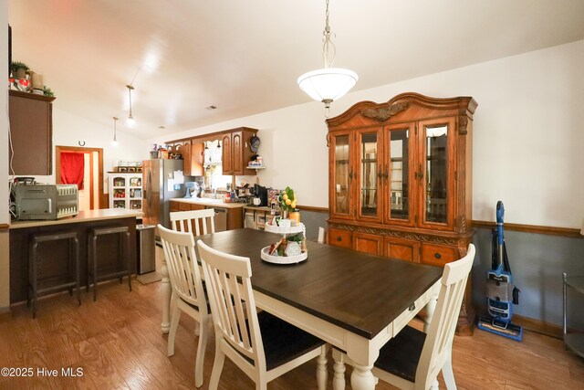 dining space featuring light wood-type flooring and lofted ceiling