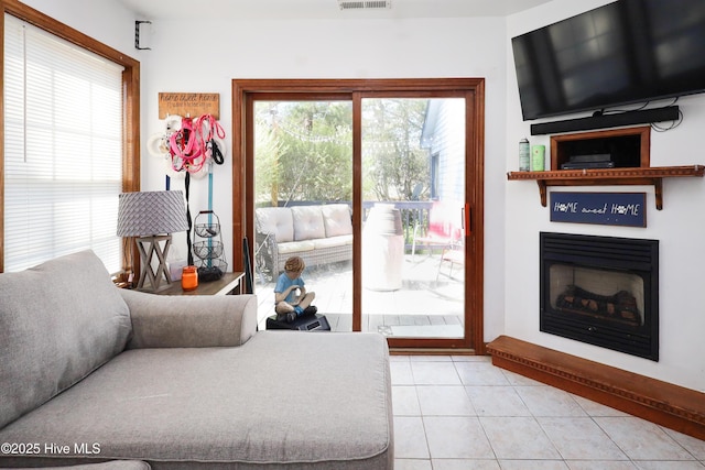 living room with a wealth of natural light, light tile patterned flooring, visible vents, and a fireplace