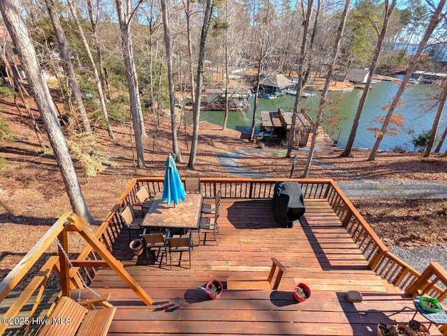 wooden deck featuring outdoor dining area, a water view, and a dock