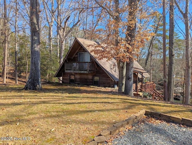 exterior space with a front lawn, a forest view, and a shingled roof