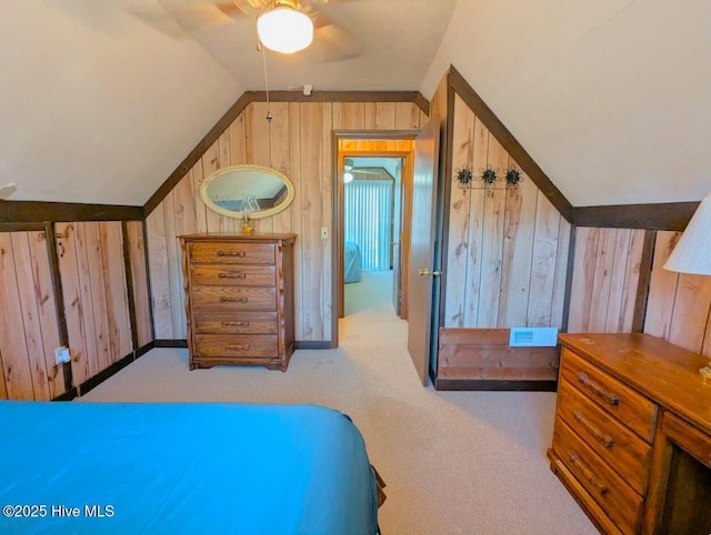carpeted bedroom with vaulted ceiling, wooden walls, and ceiling fan