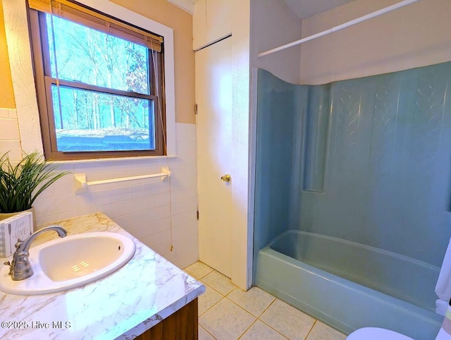 bathroom featuring tile patterned floors, a wainscoted wall, tile walls, tub / shower combination, and vanity