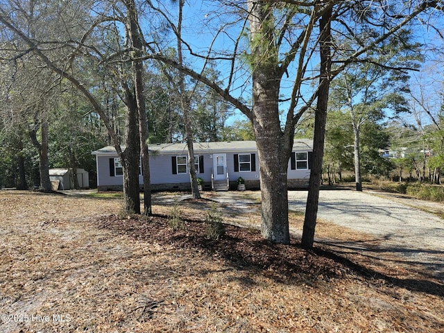 ranch-style home with a storage unit, an outbuilding, and driveway