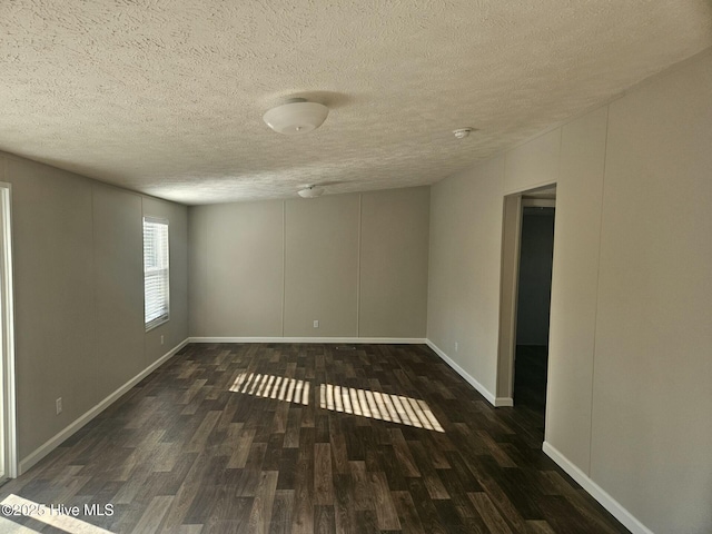 spare room featuring a textured ceiling, baseboards, and wood finished floors