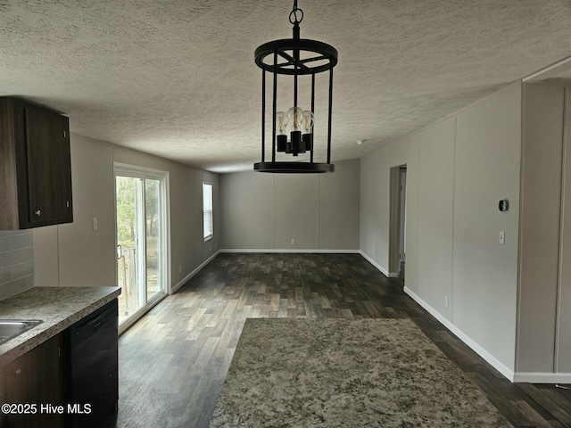 unfurnished dining area featuring baseboards, a textured ceiling, and wood finished floors