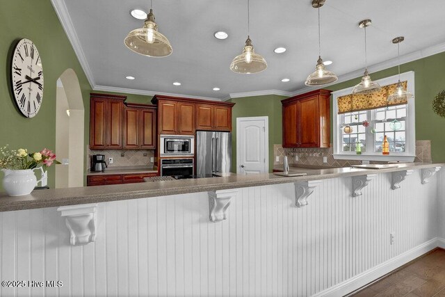 42 Harbour Village Ter, Hampstead, NC 28443 - kitchen featuring crown molding, decorative light fixtures, a peninsula, and stainless steel appliances