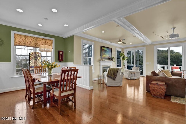 42 Harbour Village Ter, Hampstead, NC 28443 - dining space featuring crown molding, a wainscoted wall, hardwood / wood-style flooring, a glass covered fireplace, and a ceiling fan