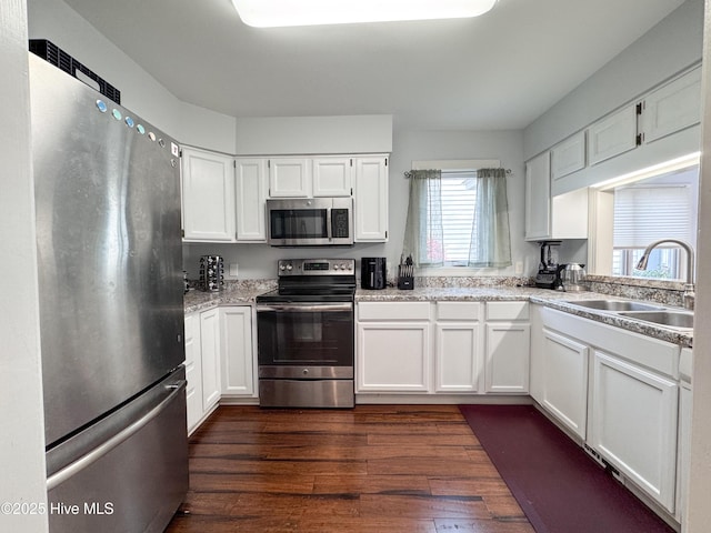 310 Wimbledon Ct, Wilmington, NC 28412 - kitchen featuring appliances with stainless steel finishes, a sink, white cabinets, dark wood-type flooring, and light stone counters