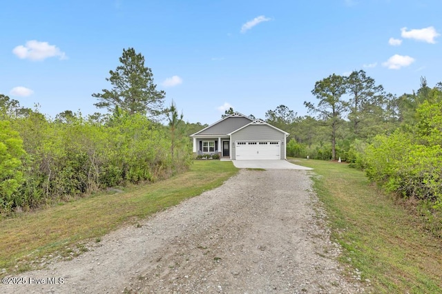view of front of property with a garage, a view of trees, dirt driveway, and a front lawn