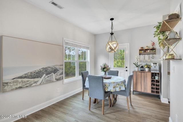 dining room with visible vents, baseboards, wood finished floors, and a notable chandelier