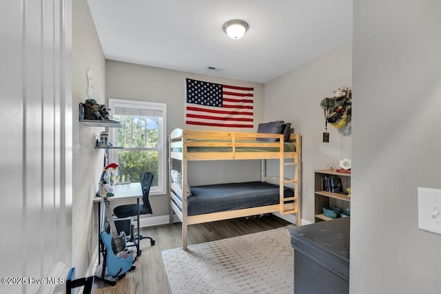 bedroom with baseboards, wood finished floors, and visible vents