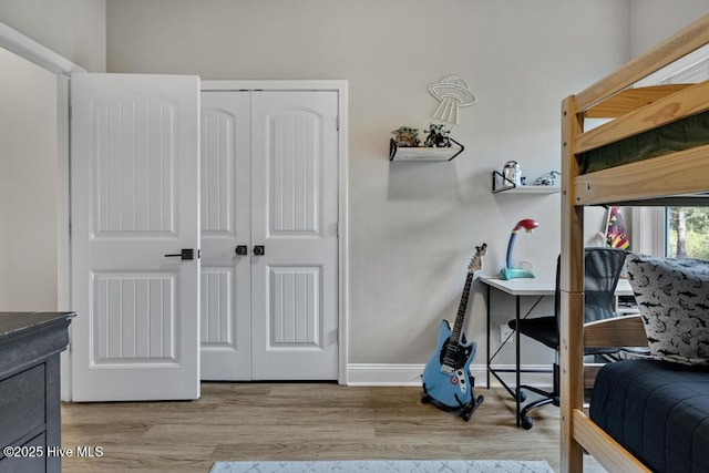 bedroom featuring light wood-style floors, baseboards, and a closet