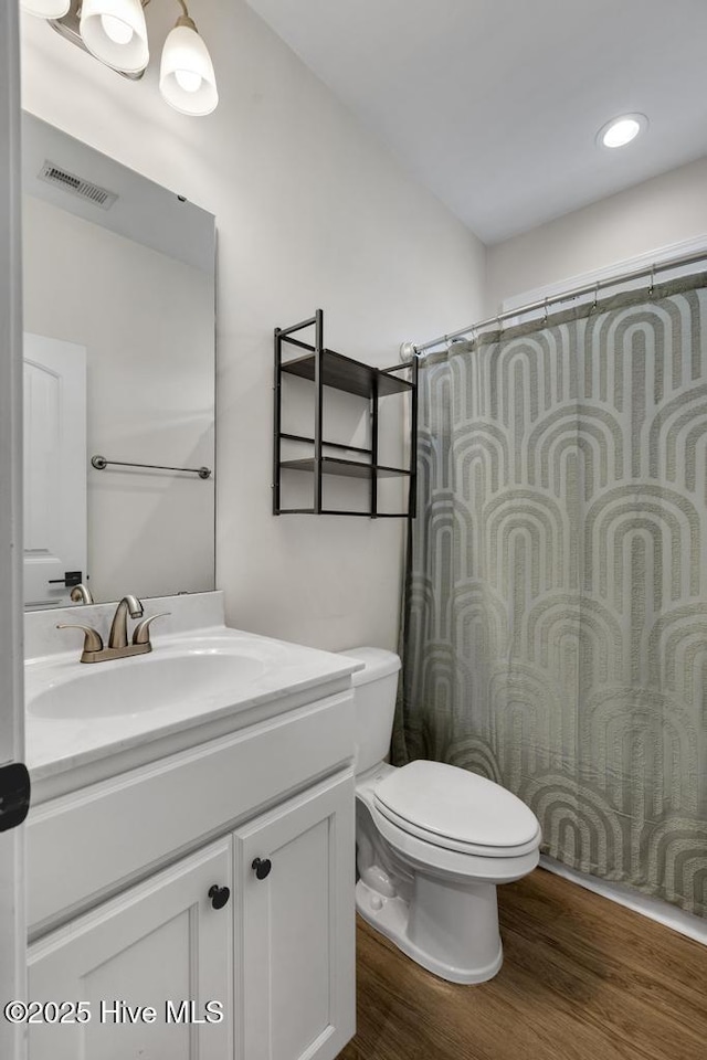 bathroom featuring visible vents, wood finished floors, toilet, and vanity