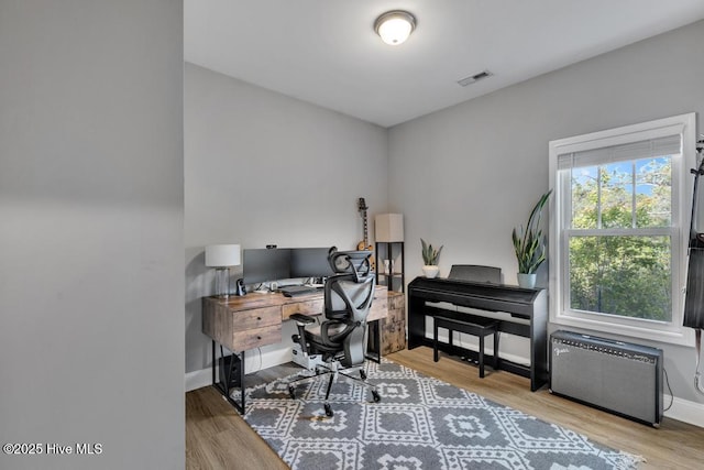 office area featuring baseboards, visible vents, and wood finished floors