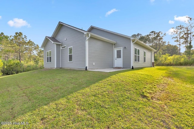 back of property with a lawn and a patio