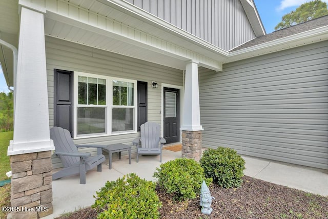 doorway to property featuring covered porch and roof with shingles