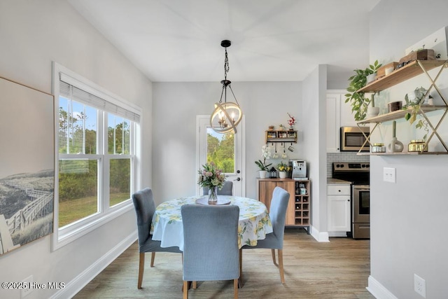 dining space featuring baseboards, light wood-style flooring, and a chandelier