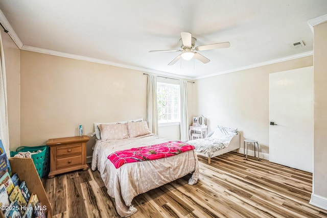 bedroom with visible vents, crown molding, baseboards, and wood finished floors