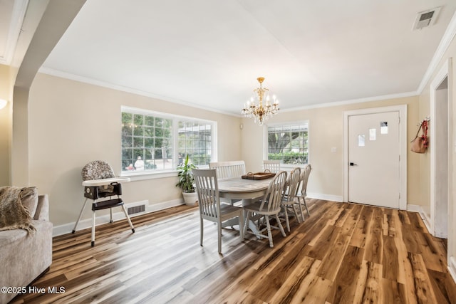 dining area featuring visible vents, crown molding, an inviting chandelier, and wood finished floors