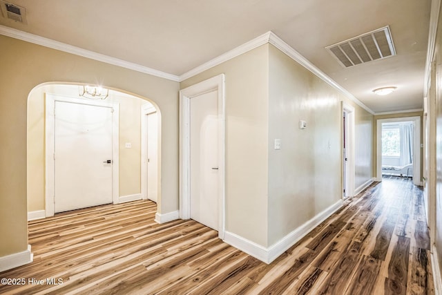 corridor featuring wood finished floors, arched walkways, visible vents, and ornamental molding