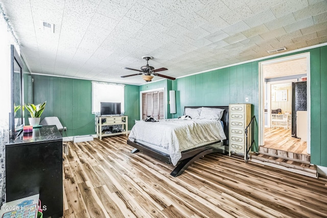 bedroom featuring crown molding, wood finished floors, visible vents, and ceiling fan