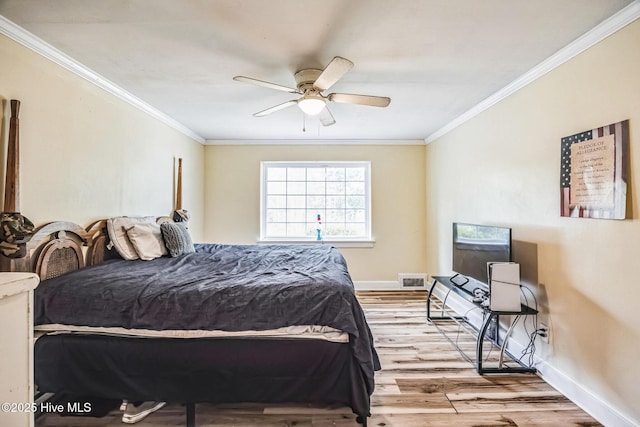 bedroom with baseboards, wood finished floors, and crown molding