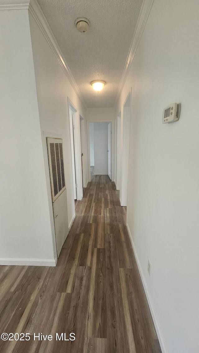 corridor with wood finished floors, a textured ceiling, and crown molding