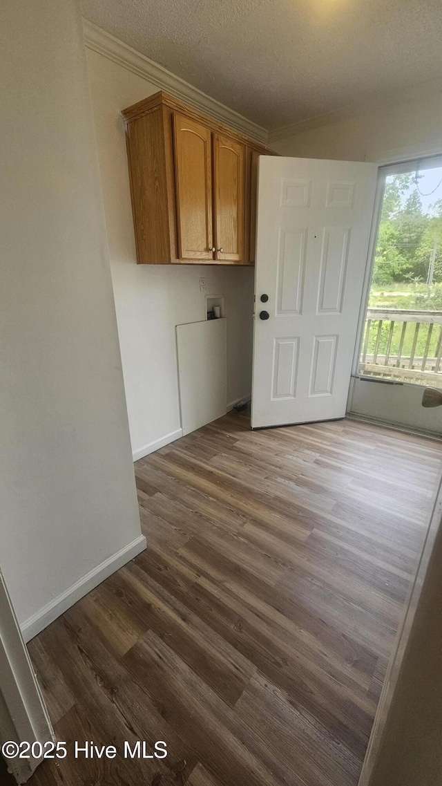 laundry area with dark wood-style floors, baseboards, cabinet space, hookup for a washing machine, and crown molding