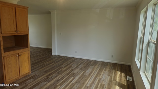 interior space with ornamental molding, dark wood-type flooring, visible vents, and plenty of natural light
